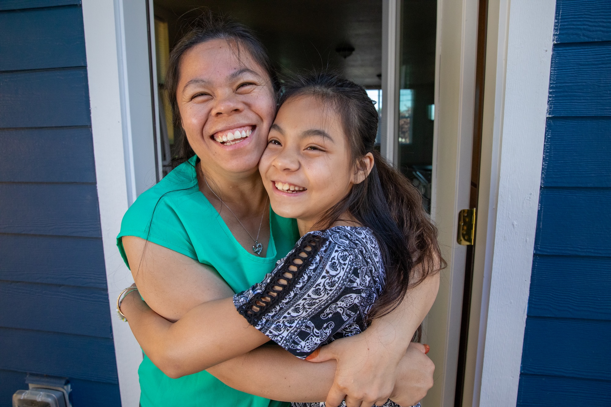 mother and daughter hugging inside of a doorway